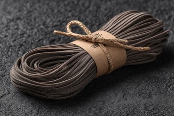 Aufkleber - Dark buckwheat noodles arranged neatly on a textured surface ready for cooking with a rustic tie