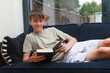 © Ben Gingell - Teenage boy on a sofa with a novel