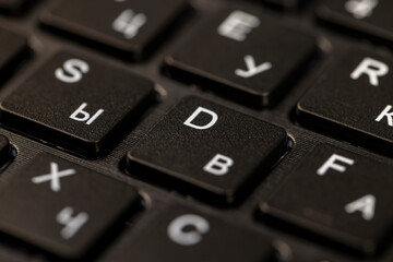 black keyboard with english and russian letters close up, the keyboard in the layout of letters in s