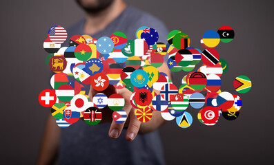 Poster - A man interacts with a digital display of flags representing countries worldwide.  Global business, communication concept.