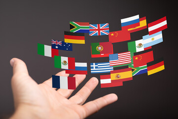 Poster - Image of a hand reaching for multiple flags representing global connectivity and international relations.