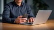 © MDSAJIB - Man in dark shirt using smartphone and laptop on wooden desk