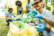 © Davide Angelini - Group of volunteer cleaning picking up plastic litter in the park - Diverse group of people collect trash in the forest - Environmental protection, non profits organization and save the planet concept