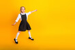 © deagreez - Young schoolgirl in uniform smiling joyfully on yellow background posing with enthusiasm, symbolizing education