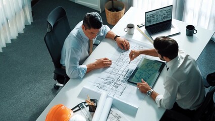 Poster - Top view of manager talk and discussing about house construction while sit and write at blueprint at meeting table with project plan laptop displayed house construction and equipment. Alimentation.