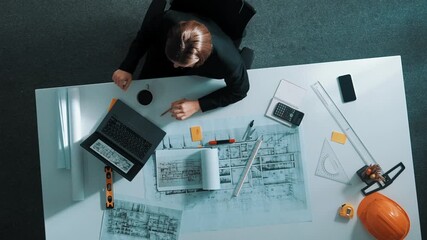 Poster - Top view of skilled designer using laptop to analysis building construction while sitting at table with safety helmet, ruler and equipment. Aerial view of manager working on computer. Alimentation.