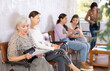 © JackF - Elderly woman in casual clothes reads text of document while sitting on chair in reception waiting for her turn