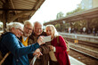 © Davor - Group of senior friends using map for directions at train station