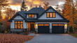 © KeJayStudio - Modern house exterior with black garage doors and warm interior lights glowing through windows during autumn sunset surrounded by colorful fall trees and fallen leaves