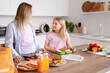 © Pixel-Shot - Happy mother with daughter cooking food for school lunchbox in kitchen