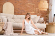 © Pixel-Shot - Young pretty woman sitting on floor near sofa in beautiful living room