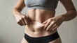 © Fitra - Young Woman Pinching Stomach Skin Excess Belly Fat Weight Gain Concept