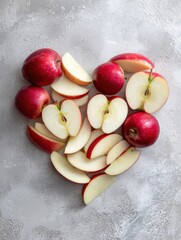 Poster - Sliced Apples Arranged in a Heart Shape for a Healthy and Wellness-Focused Presentation on a Gray Surface