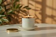 © SayedMahbub - A lit speckled white candle with a copper rim sits on a saucer next to its lid on a white table with dappled light