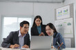 © crizzystudio - Asian businesspeople working together, analyzing data on laptop, discussing project strategy in office meeting