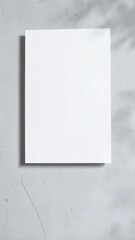 Poster - A blank white rectangular sheet of paper is adhered to a textured light gray wall with a leafy shadow overlay