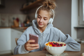 Poster - A girl is sitting at a table with a bowl of fruit in front of her