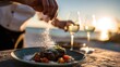 © Hungarian - A chef sprinkles salt over a steak dinner served outdoors.