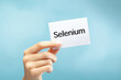 © DaniLana - Close-up of female hand holding white sign with text 'Selenium' on light blue.