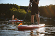 © Serhii - Sportsman paddling on sup board at sunset on lake with pedal boat in background
