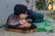 © Mikhail - A homeless and desperate man sleeping on a dirty mat in the street. Poverty concept