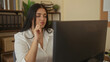 © Krakenimages.com - Woman working at computer in an office, focused on task, surrounded by books and greenery, wearing casual attire, capturing the essence of modern workplace.
