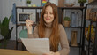 © Krakenimages.com - Woman smiling in an office holding glasses and reading a document, surrounded by plants and shelves, suggesting a casual and modern work environment.