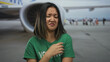 © Krakenimages.com - Young woman volunteer makes a disgusted face at an airport terminal with a plane in the background outdoors, conveying travel-related emotion.