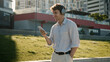 © Yuliia - Happy Caucasian young man listening music on headphones energetic carefree male city guy dancing moving song playlist audio weekend pleasure mobile phone student businessman technology outdoors fun