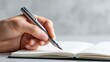 © AI Images - Close up of hand writing in a notebook with a pen on a gray background.