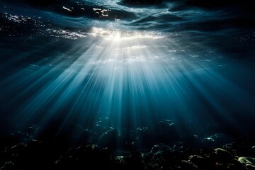 Poster - Dramatic sunbeams pierce through ocean surface creating ethereal underwater light rays in deep blue water with rocky seafloor beneath. Perfect for nature themes.