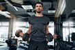 © Valerii Apetroaiei - Young athletic man performing biceps curls with dumbbells in a modern gym. Strength and determination. Concept: fitness, workout, motivation.