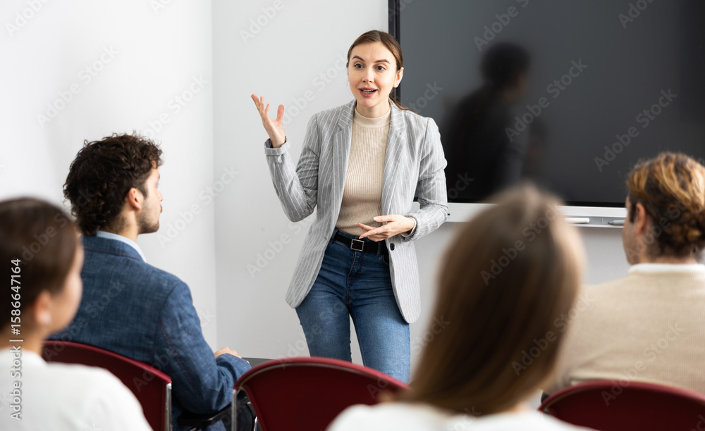 Young female tutor teaching students in college classroom