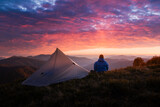 Autumn mountains glow under vibrant sunset as hiker rests near his tent. Peaceful fall scenery shown with rich evening tones and serene outdoor camping Autumn mountains glow under vibrant sunset as hiker rests near his tent. Peaceful fall scenery shown with rich evening tones and serene outdoor camping
