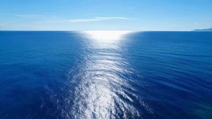 Poster - Vast expanse of blue ocean water shimmering under the sunlight with clear sky and distant land for an idyllic seascape panorama
