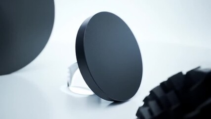Poster - Dark Gray Circular Disc with Abstract Elements on White Surface in Soft Lighting Studio for Product Showcase Display