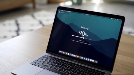 Poster - Silver Laptop Displaying Progress Indicator on Wooden Table with Blurred Rug Background