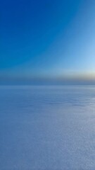 Poster - Endless expanse of tranquil blue sea with gentle ripples under clear skies and distant horizon with soft mist at water level