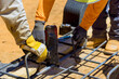 © ungvar - Workers collaborate to secure rebar on wooden mold at construction site under construction work day