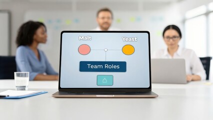 Fototapete - Laptop displaying team roles diagram with two women and a man in a meeting setting.