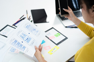 Fototapete - Website designer, Creative planning phone app development template layout framework wireframe design, User experience concept, Young asian UX designer working on smartphone application at office.