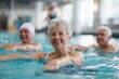 © TashaAsha - Group of elderly men and woman exercising in indoor swimming pool during water aerobics class