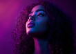 © Yuliia - Young African American woman with natural curly hair in dramatic purple and blue neon lighting, looking up with parted lips, creating atmospheric nightclub mood.