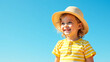 © Galeno - smiling girl curly blonde hair wears bright yellow striped onesie matching sun hat standing radiant