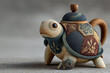 © AmayaGB - tetera con forma de tortuga hecha de arena petrificada, visualmente parece antigua, precolombina, ancestral, va como caminando invitando un té sobre fondo gris claro, aislado, espacio copy