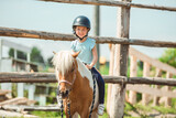 Cute little girl petting a pony in a farm