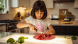 © nixartmd - A young girl carefully slices strawberries on a cutting board in a well-lit kitchen