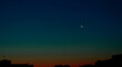 © Oleksandr - Crescent moon in the twilight sky over the silhouettes of city buildings creates a serene and peaceful atmosphere during the early evening hours .