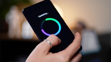 Poster - Hand Holding Smartphone with Circular Loading Animation Against Blurred Background in Soft Indoor Lighting