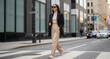 © ViskBx - Stylish woman in a blazer and trousers confidently strides across a crosswalk in the city, showcasing chic urban fashion with sunglasses.